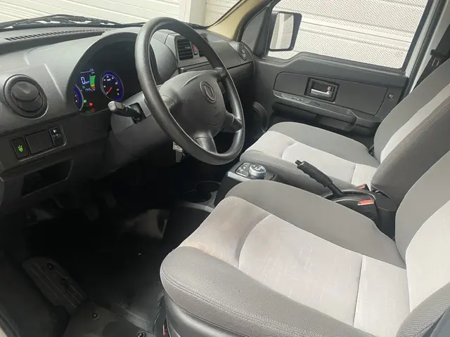 Intérieur avant du DFSK EC35 blanc, vue côté conducteur, volant multifonctions et tableau de bord digital lumineux visible.