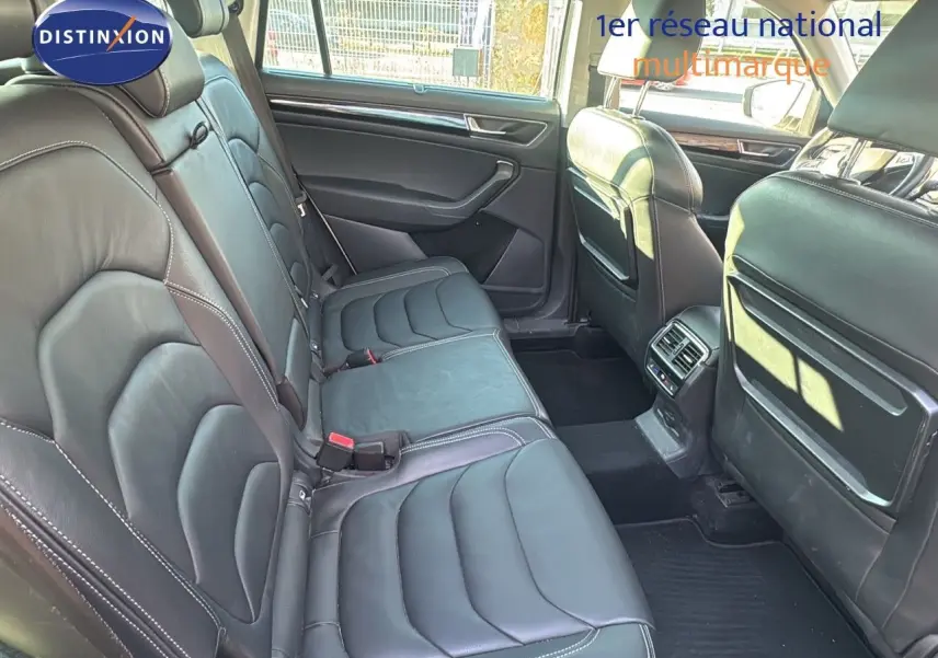 Vue intérieure sur la banquette arrière en cuir noir du Skoda Kodiaq blanc, mettant en valeur l'espace et les finitions soignées.