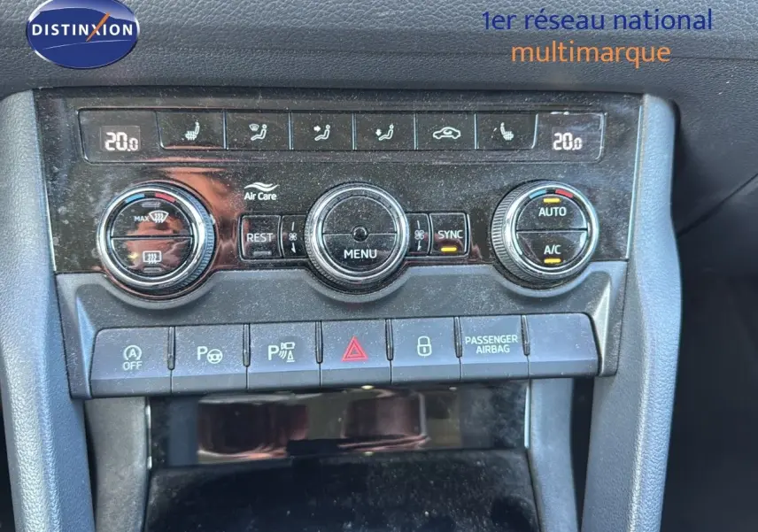 Vue rapprochée du tableau de bord central du Skoda Kodiaq blanc, montrant les commandes de climatisation et les boutons de sécurité.