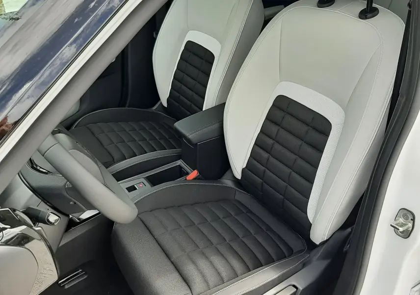 Vue intérieure rapprochée des sièges avant bicolores noirs et blancs du Citroën C3 Aircross 2026, porte ouverte côté conducteur.