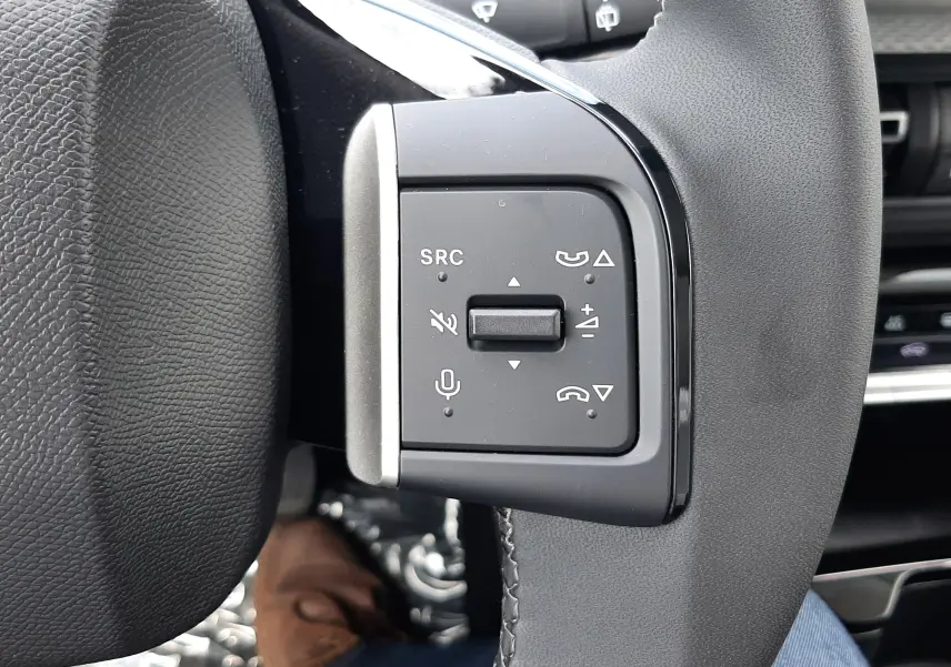 Gros plan sur les commandes gauche du volant du Citroën C3 Aircross blanc banquise, avec boutons de volume et appel.