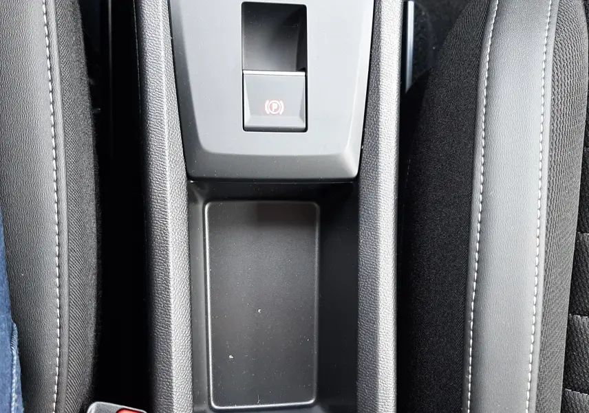Vue plongeante sur la console centrale noire du Citroën C3 Aircross 1.2 Hybrid 145, avec frein à main électrique et rangement.