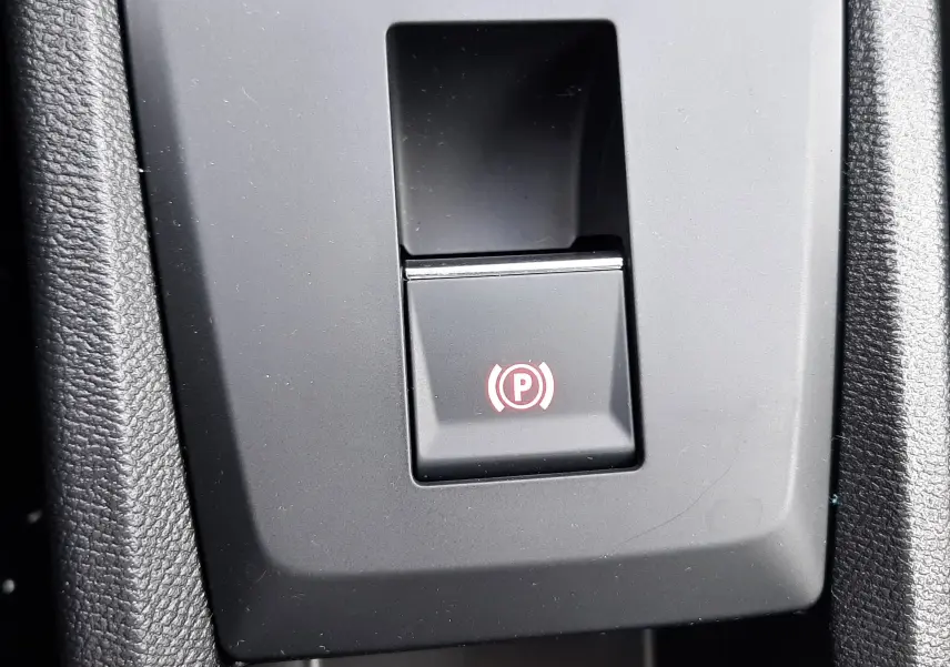 Gros plan sur le bouton de frein à main électronique avec symbole rouge dans l'habitacle du Citroën C3 Aircross blanc banquise.