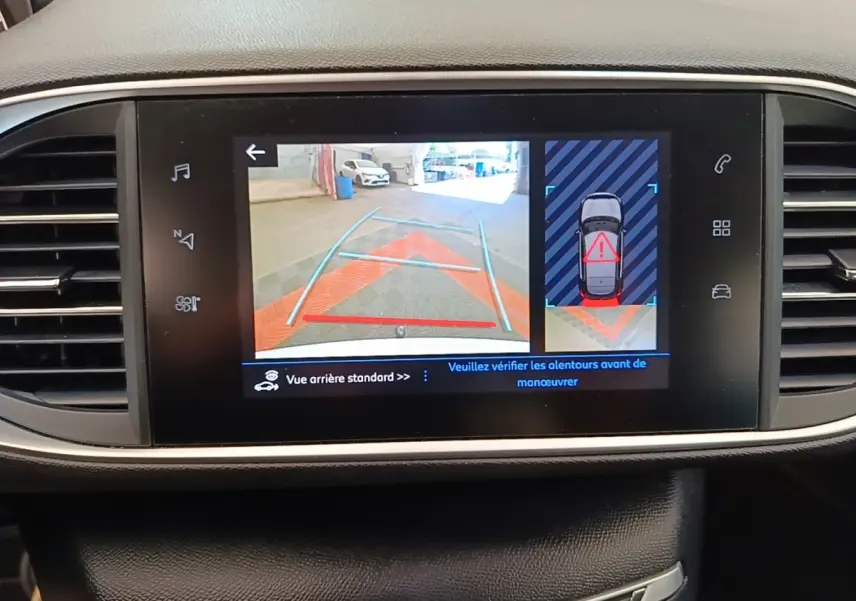 Écran tactile intérieur de la Peugeot 308 blanc montrant la caméra de recul et l'alerte de proximité arrière.