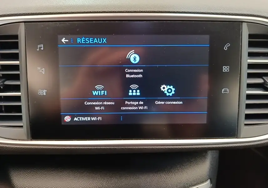 Écran tactile central de la Peugeot 308 blanc, affichant le menu de connexion Bluetooth et Wi-Fi, intérieur noir.