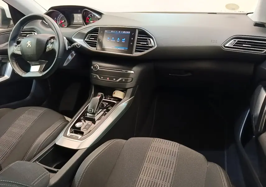 Vue intérieure côté conducteur de la Peugeot 308 2020 avec tableau de bord noir et écran tactile central lumineux.