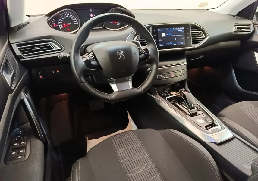 Vue intérieure avant droite de la Peugeot 308 avec volant cuir, écran tactile central et console de boîte automatique.