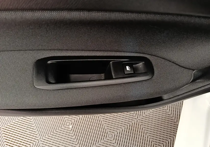 Poignée intérieure de porte côté conducteur d'une Peugeot 308 blanche, avec bouton de verrouillage intégré.