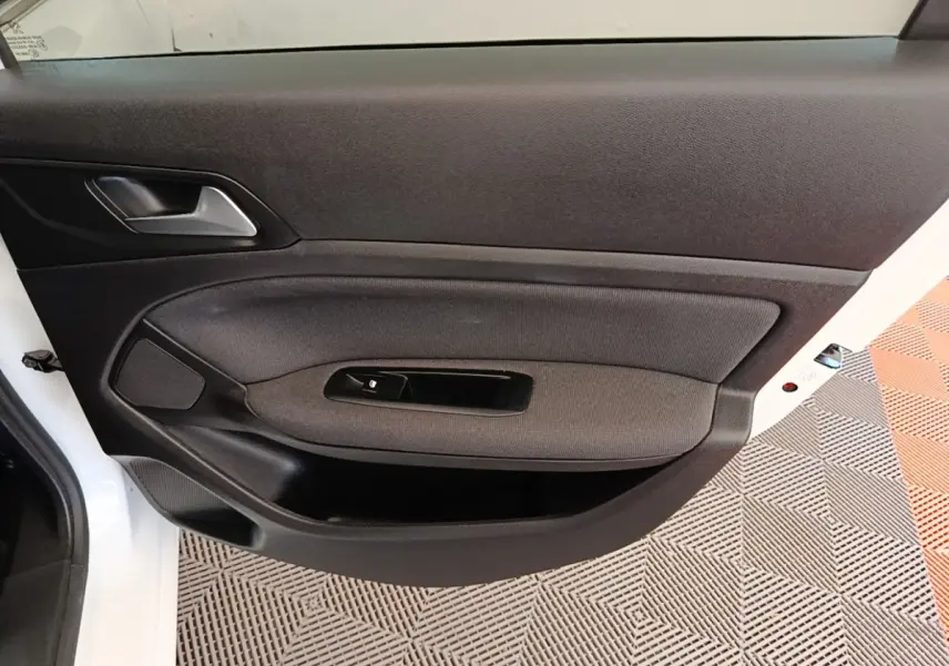 Vue rapprochée de la porte avant gauche blanche d'une Peugeot 308 avec garniture noire et commande de lève-vitre.