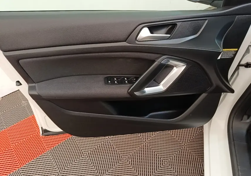 Vue rapprochée de la porte avant gauche blanche d’une Peugeot 308 2020 avec garniture noire et commandes de vitres.
