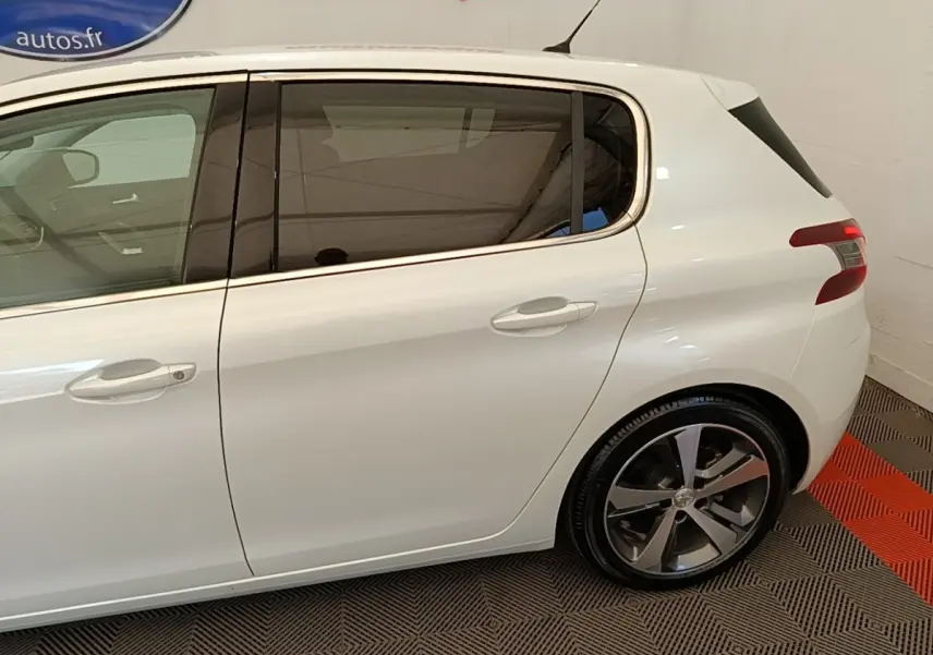 Profil côté gauche de la Peugeot 308 blanche, mettant en valeur les vitres teintées et les jantes alliage.