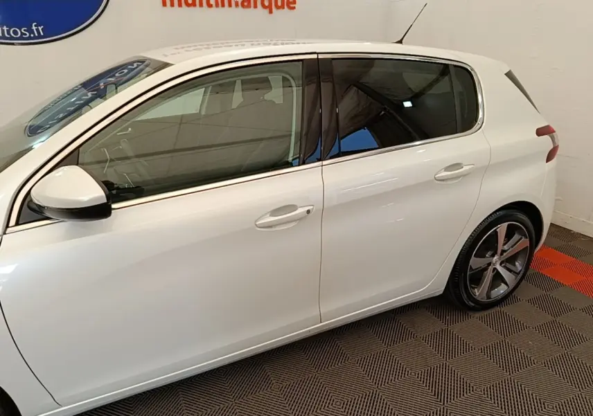 Profil côté gauche d'une Peugeot 308 blanche de 2020, avec jantes alliage et vitres teintées visibles.