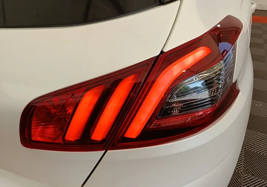 Gros plan sur le feu arrière droit rouge allumé d’une Peugeot 308 blanche, version BlueHDi 130 de 2020.