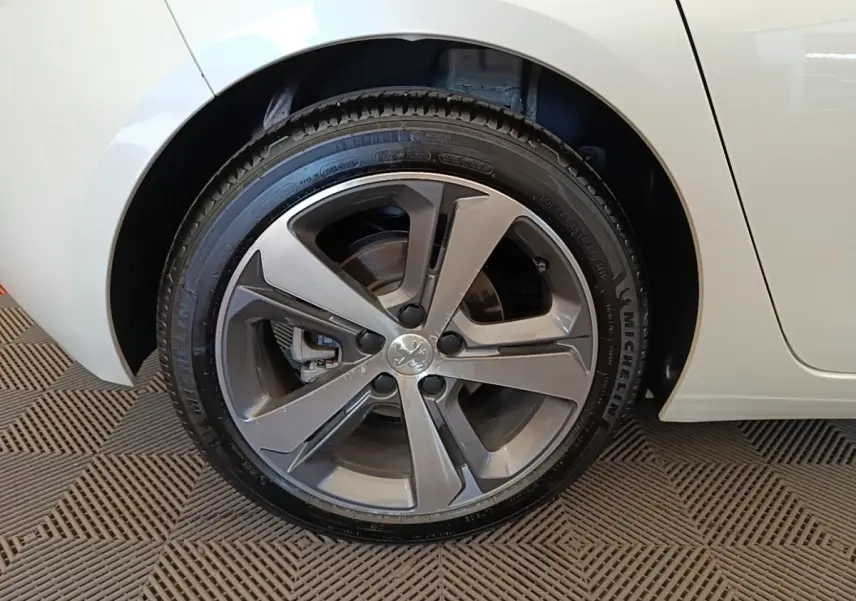 Gros plan sur la roue arrière droite d'une Peugeot 308 blanche, avec jante alliage gris foncé et pneu Michelin.