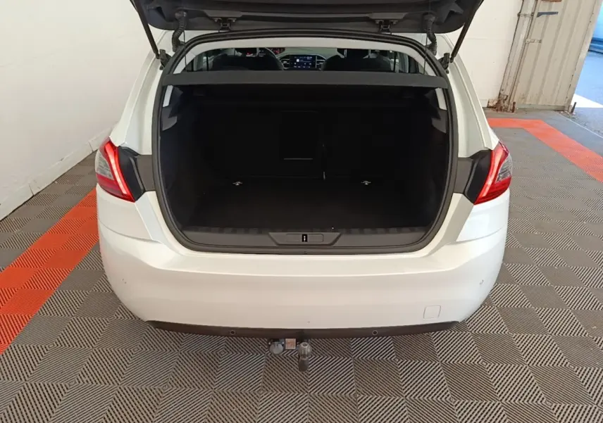 Vue arrière ouverte d'une Peugeot 308 blanche montrant le coffre spacieux et l'attelage de remorque.