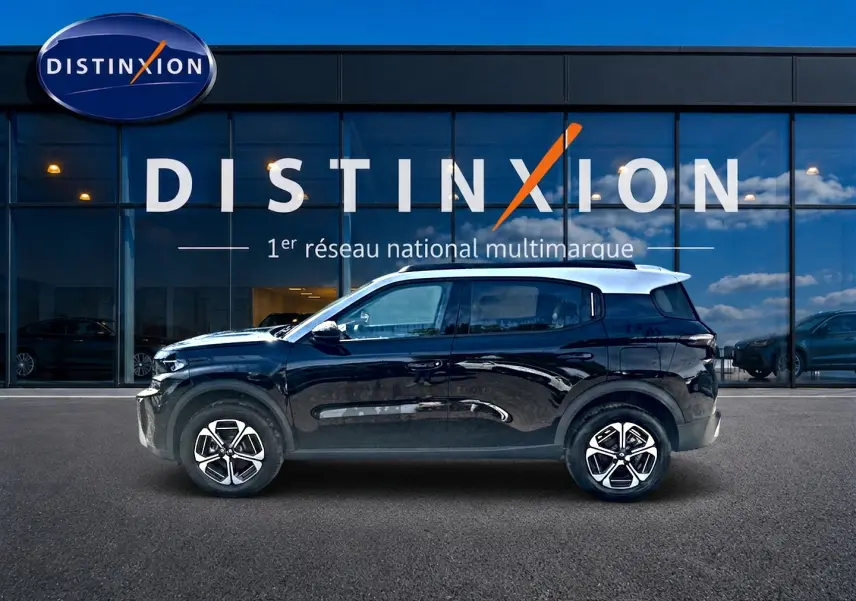 Profil côté gauche d'un Citroën C3 Aircross noir 2026, avec jantes alu et toit blanc devant une vitrine Distinxion.