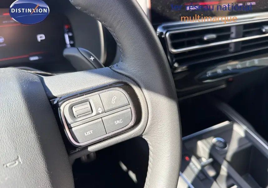 Gros plan sur le volant noir de la Citroën C5 Aircross 2023, montrant les commandes audio et téléphone côté gauche.