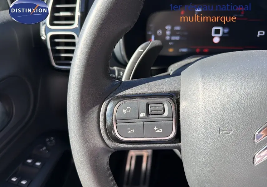 Gros plan sur le volant cuir du Citroën C5 Aircross blanc nacré, avec commandes audio intégrées à gauche.