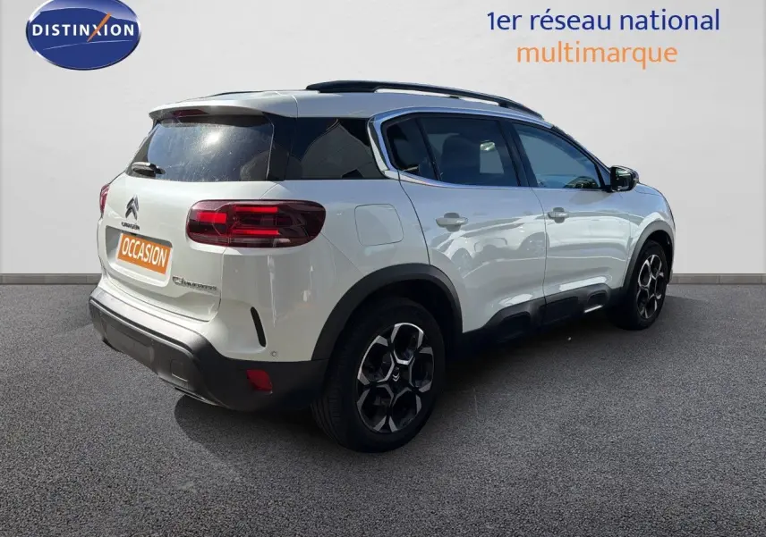 Vue 3/4 arrière droite d'un Citroën C5 Aircross blanc nacré avec toit noir et jantes noires distinctives.