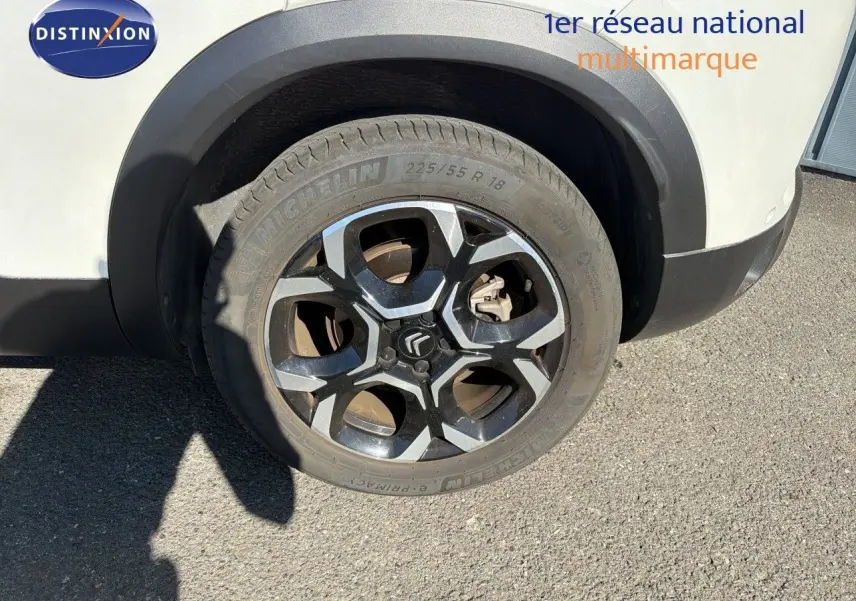 Gros plan sur la roue avant droite du Citroën C5 Aircross blanc nacré avec jante alliage noire et argentée.