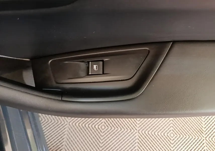 Gros plan sur la commande de lève-vitre côté gauche de la porte intérieure d’une Peugeot 508 gris foncé.