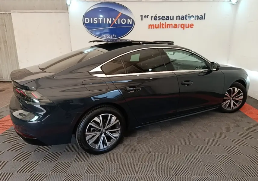 Peugeot 508 gris foncé vue de profil côté gauche, avec jantes alliage et vitres teintées dans un showroom.