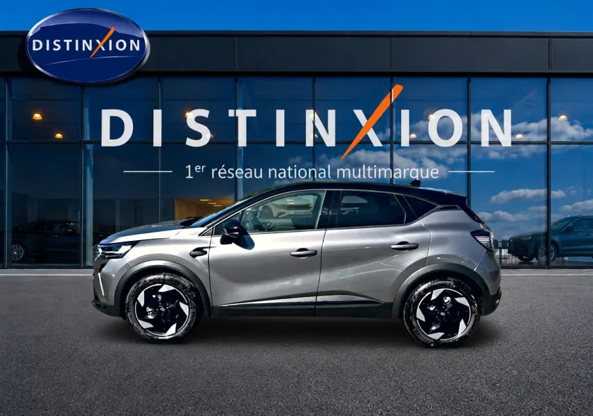 Renault Captur gris Cassiopée vu de profil côté gauche devant une vitrine Distinxion, jantes noires et blanches.