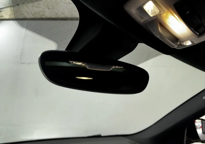 Vue intérieure centrée sur le rétroviseur intérieur et le plafonnier éclairé d’un BMW X2 blanc hybride rechargeable 2022.