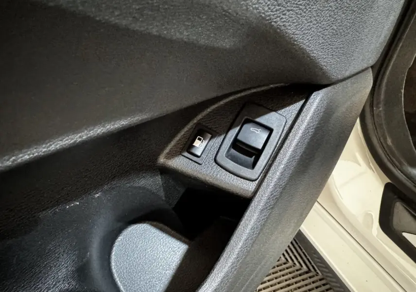 Détail des commandes d’ouverture du coffre et de la trappe à carburant sur la porte côté gauche d’un BMW X2 blanc.