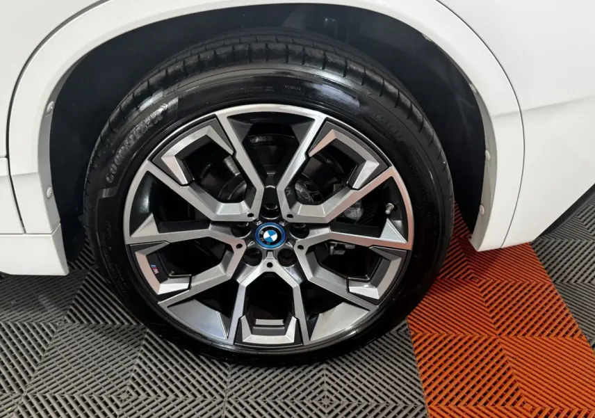 Gros plan sur la roue avant droite d’un BMW X2 blanc avec jante alliage M Sport au design géométrique.
