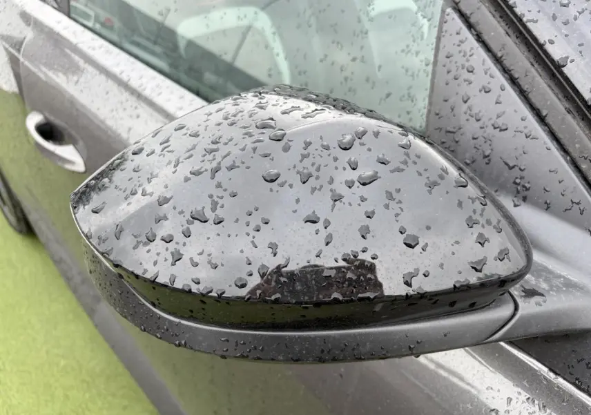Rétroviseur extérieur droit noir brillant d'un Citroën C5 Aircross Platinium avec gouttes de pluie visible de près.