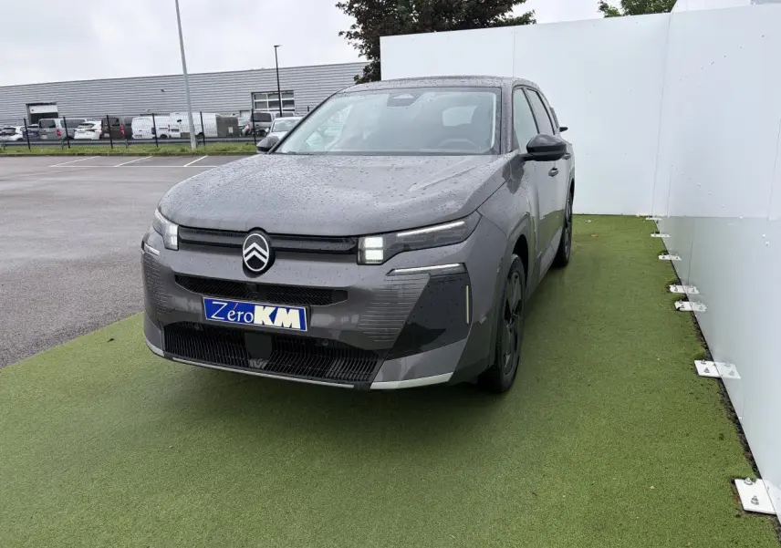 Vue 3/4 avant d’un Citroën C5 Aircross 2026 gris Platinium avec toit noir et calandre distinctive sur fond vert.
