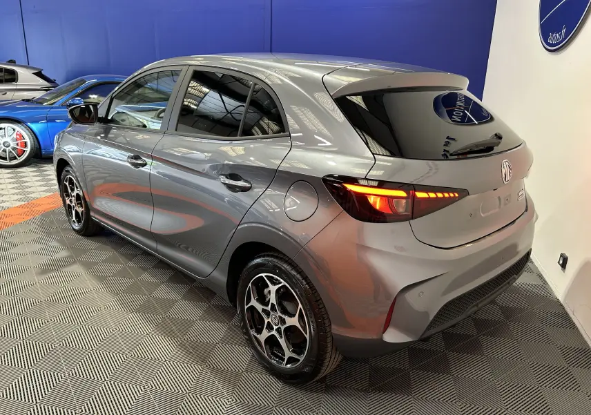 Vue 3/4 arrière droite du MG3 1.5 Hybrid+ 195 Luxury en gris Hampstead avec feux arrière allumés et jantes distinctives.