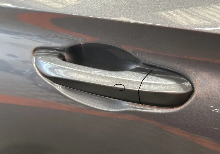 Poignée de porte côté gauche de la MG3 1.5 Hybrid+ 195 Luxury en couleur Hampstead Grey avec bouton de déverrouillage intégré.