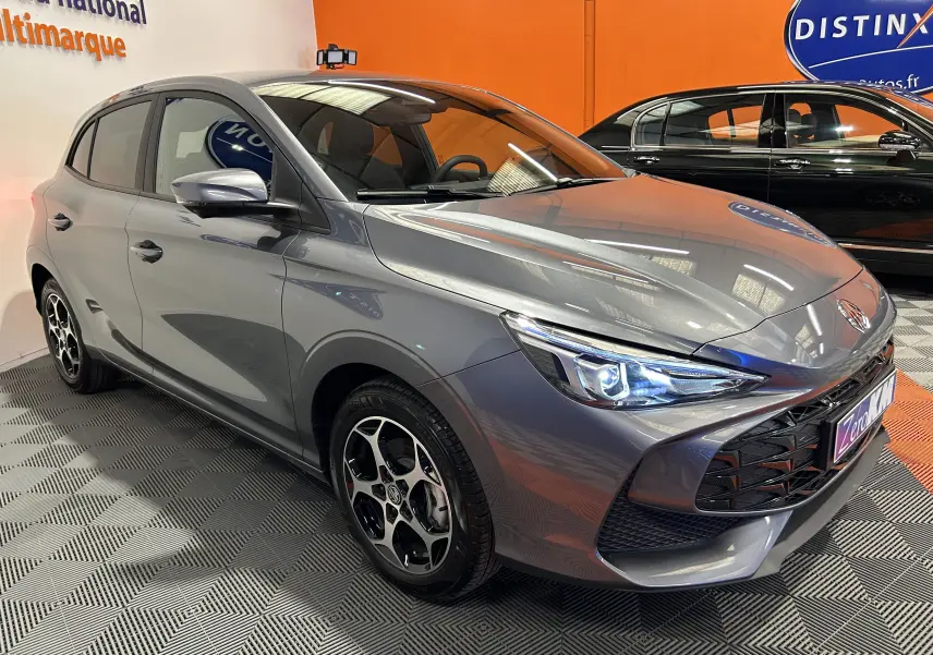 MG3 1.5 Hybrid+ 195 Luxury gris Hampstead en 3/4 avant droit, avec phares LED allumés et jantes distinctives.