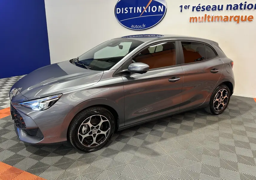 Vue 3/4 avant droite de la MG3 1.5 Hybrid+ 195 Luxury gris Hampstead avec jantes noires et intérieur marron visible.