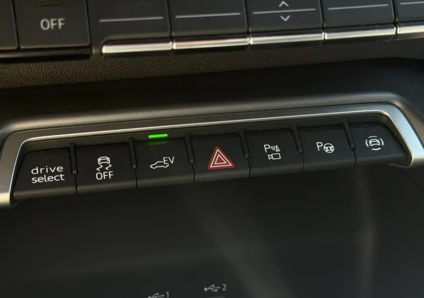 Gros plan sur les boutons de commande du tableau de bord de l'Audi A3 Sportback bleu Navarre, avec témoin EV vert allumé.