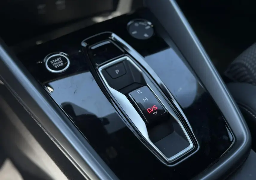 Gros plan sur la console centrale noire brillante avec sélecteur de boîte auto et bouton Start/Stop de l'Audi A3 Sportback.