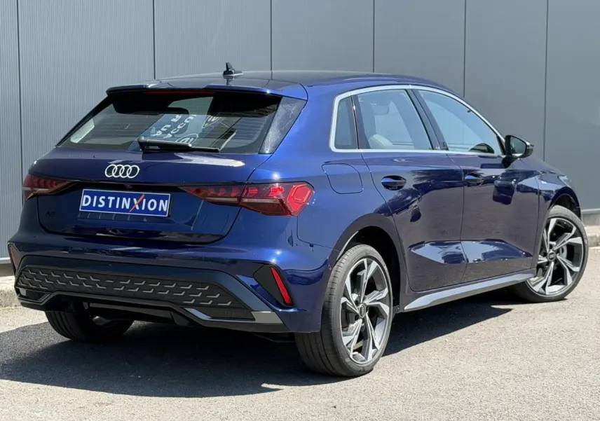 Vue 3/4 arrière droite d'une Audi A3 Sportback 2025 bleu Navarre avec jantes alliage 18 pouces et feux LED dynamiques.