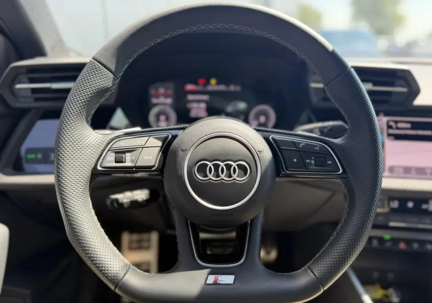 Volant sport Audi S avec commandes multifonctions en cuir perforé, vue frontale de l’habitacle de l’Audi A3 Sportback 2025.