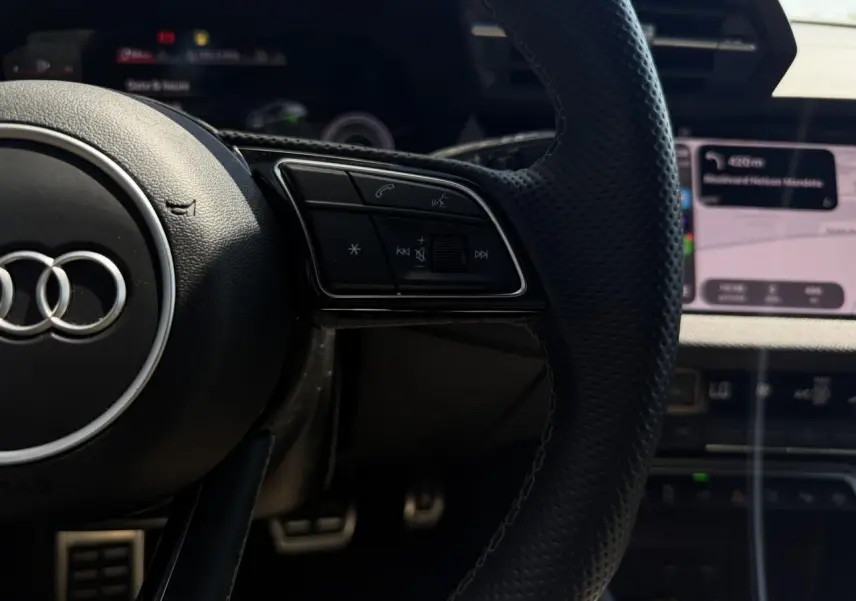 Gros plan sur le volant cuir perforé de l'Audi A3 Sportback 2025 avec commandes multifonctions et tableau de bord numérique.