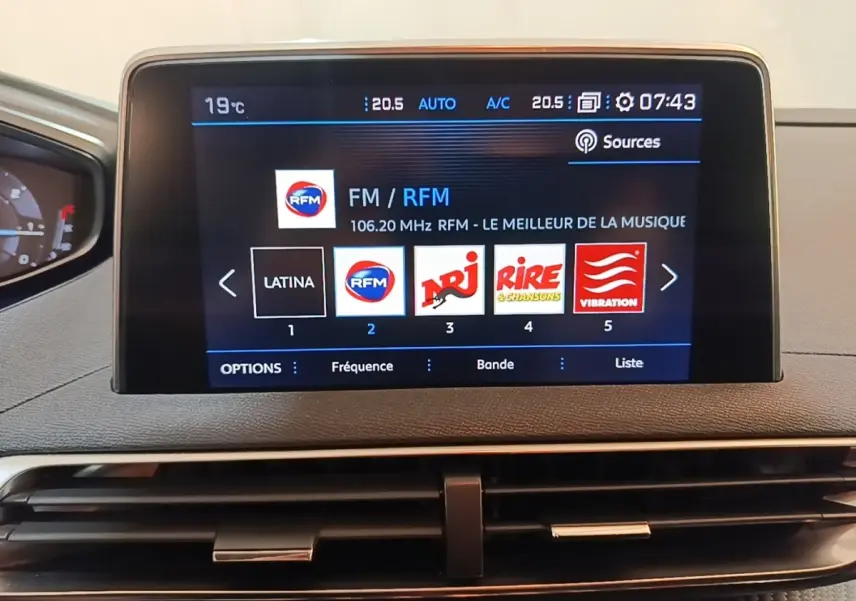 Écran tactile central du tableau de bord du Peugeot 5008 noir, affichant les stations radio FM avec interface moderne.