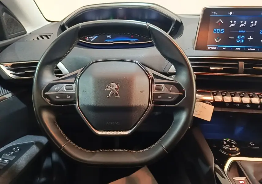 Vue centrée sur le volant cuir noir du Peugeot 5008 2018 avec tableau de bord digital et écran tactile de climatisation.