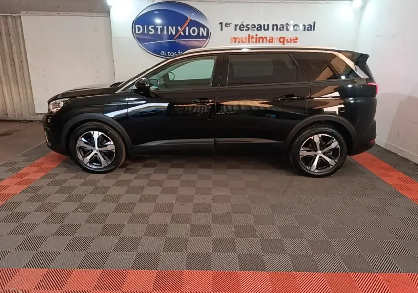 Peugeot 5008 noir vue de profil côté gauche, avec jantes alliage et vitres teintées dans un showroom.