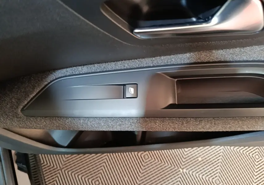 Gros plan sur la poignée intérieure et le bouton de verrouillage de la porte côté conducteur du Peugeot 5008 noir.