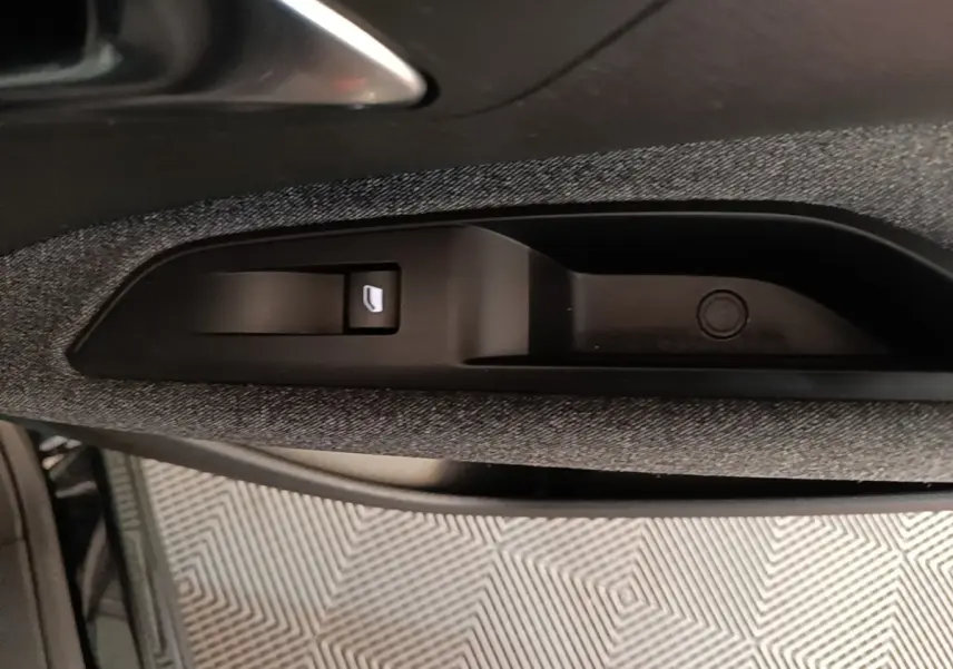 Gros plan sur la commande de lève-vitre électrique intégrée dans la porte côté conducteur du Peugeot 5008 noir.