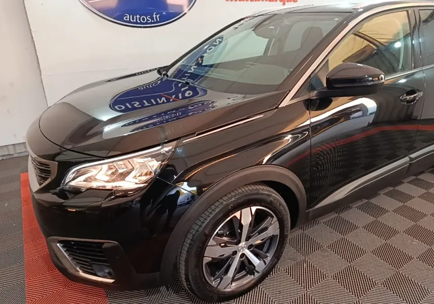 Vue 3/4 avant droit du Peugeot 5008 noir avec phares allumés et jantes alliage modernes.