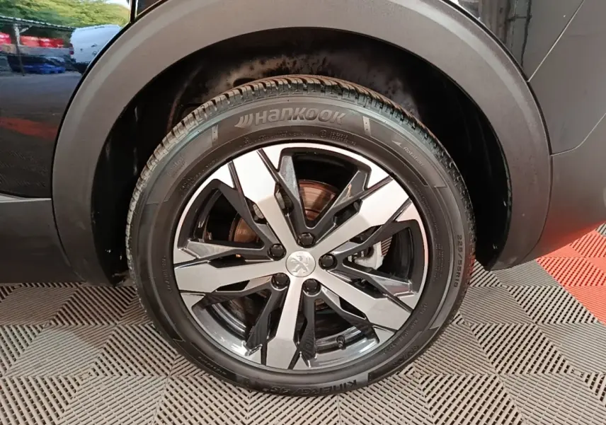 Gros plan sur la roue avant droite noire du Peugeot 5008 avec jante alliage bicolore et pneu Hankook.