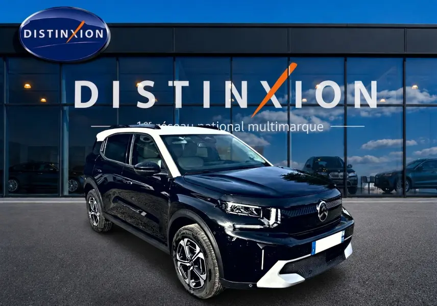 Vue 3/4 avant droite du Citroën C3 Aircross noir avec toit blanc, jantes alu et calandre moderne devant un showroom Distinxion.