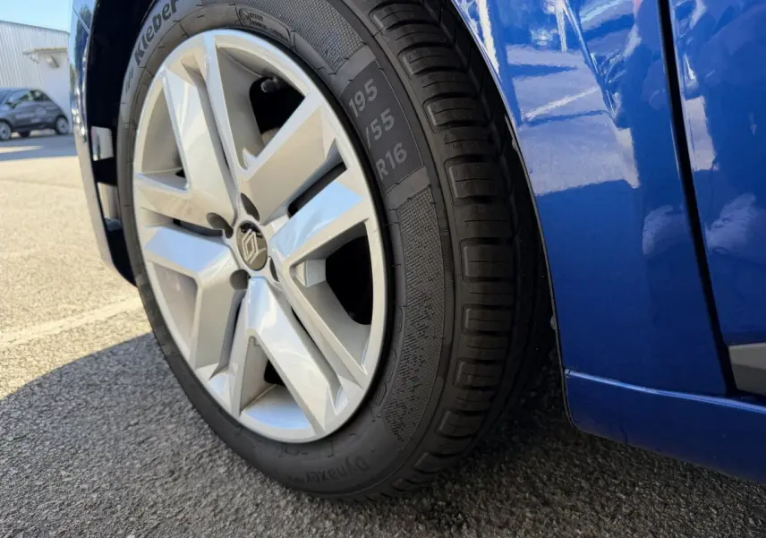 Gros plan sur la roue avant gauche et la partie basse bleue d'une Renault Clio Evolution TCe 90 2024.